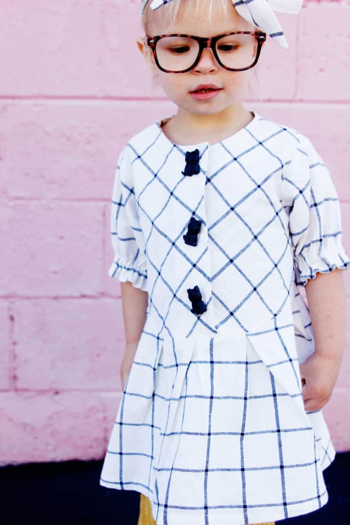 Zig Zag Dress pattern gives a preppy look with it's plaid and pleats! It's curved bodice gives it a really cute swing! Elastic sleeves, big buttons, and facing on the inside makes this dress a dress to love! || See Kate Sew #dresspatterns #kidsfashion #dresses #seekatesew